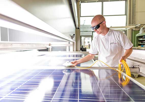 Mann mit einem stationären Sonnensimmulator der auf das Photovoltaik Modul zeigt