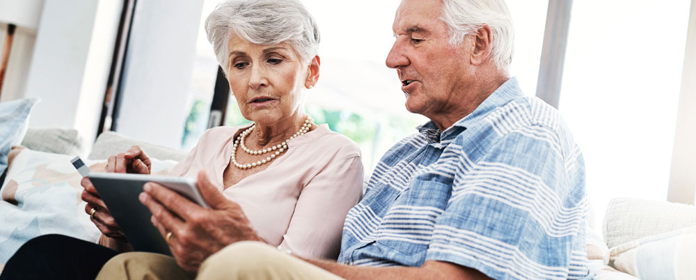 Zwei ältere Menschen betrachten ein Tablet