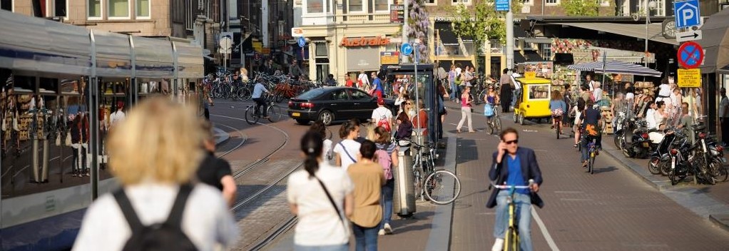Ausschnitt des Stadtlebens, Fußgänger, eine Straßenbahnstation und Radfahrer