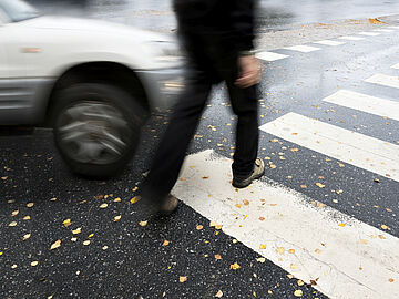 a car almost hitting a pedestrian while on the crosswalk