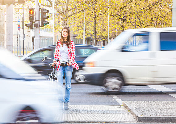 Person geht über einen Zebrastreifen, obwohl die Ampel rot zeigt. Autos fahren weiter.